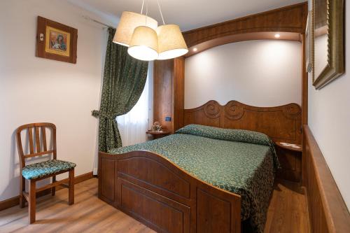 a bedroom with a wooden bed and a chair at Rifugio Cereda in Fiera di Primiero