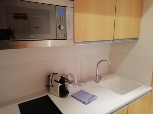 a kitchen with a sink and a microwave at Apartamento Praia do Relógio in Figueira da Foz