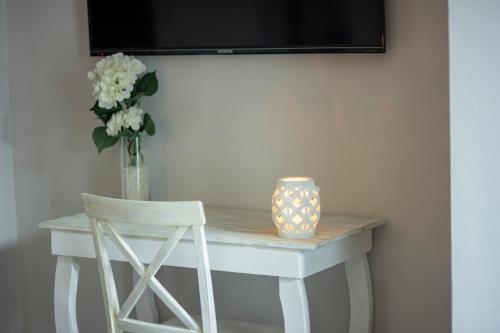 a white table with a vase of flowers and a chair at Hotel Venedik in Veracruz