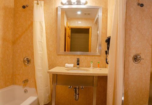 a bathroom with a sink and a tub and a mirror at Elmhurst Hotel in Queens