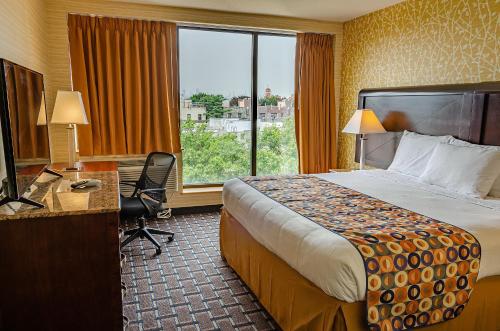 una camera d'albergo con letto, scrivania e finestra di Elmhurst Hotel a Queens