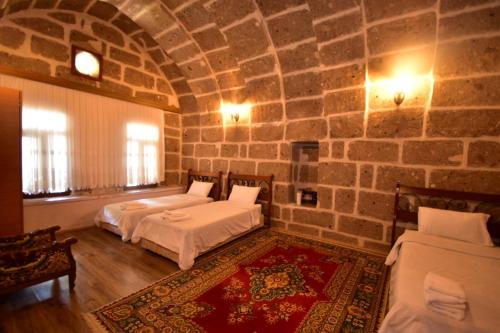 a bedroom with two beds and a stone wall at Kapadokya Ihlara Günalp Konağı in Guzelyurt