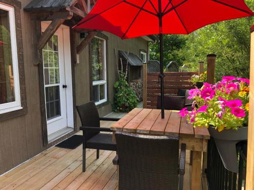 a wooden table with a red umbrella on a deck at Chalets et Studios Le Vent Du Nord in Lac-Superieur