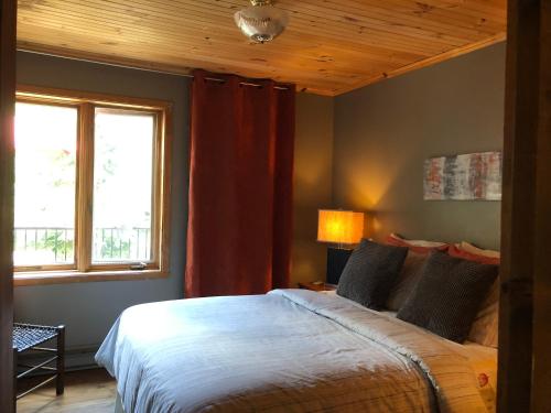 a bedroom with a bed and a window at Chalets et Studios Le Vent Du Nord in Lac-Superieur