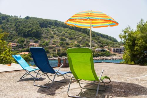three lawn chairs and an umbrella on a patio at Apartment Dijana in Prigradica