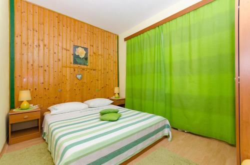 a bedroom with a bed with a green curtain at Apartment Slavka in Račišće