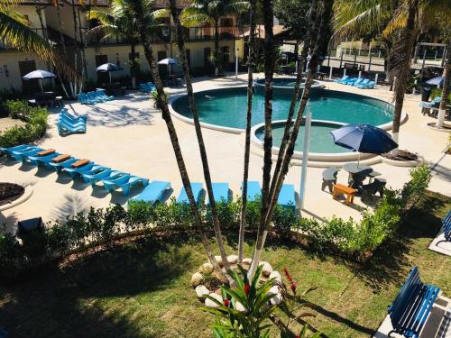an outdoor pool with chairs and umbrellas and a resort at Pousada Ilha Vitoria in Ubatuba