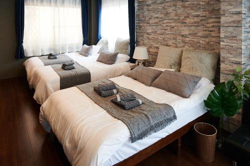 two beds in a room with a brick wall at Ueno Residence Hotel Matsumoto in Tokyo