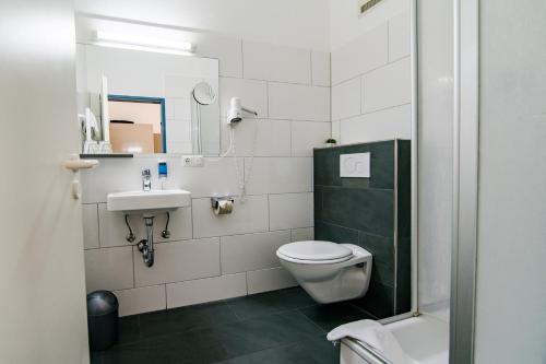 
a white toilet sitting next to a white sink in a bathroom at Hotel Weidenhof in Regensburg
