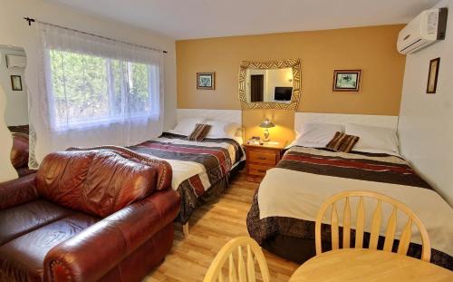 une chambre d'hôtel avec deux lits et un canapé dans l'établissement Motel des Deux Lacs, à Waterloo