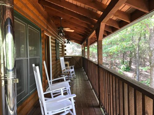 a porch of a cabin with white chairs on it at Barefoot Hills in Dahlonega