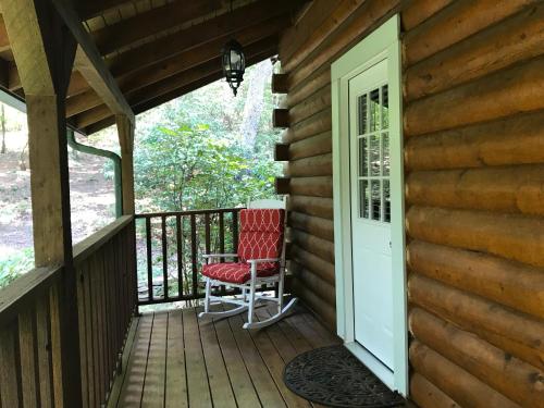 a porch with a red chair and a white door at Barefoot Hills in Dahlonega