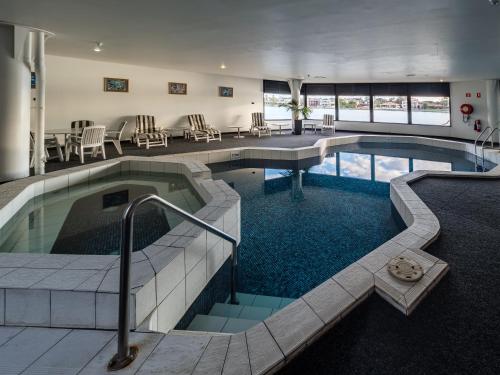 una piscina en un hotel con sillas y mesas en Lakes Hotel en Adelaida