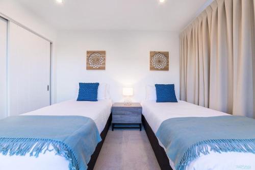 two beds sitting next to each other in a room at Executive Living in Bluewater - 3 Bedroom Apartment in Queenstown