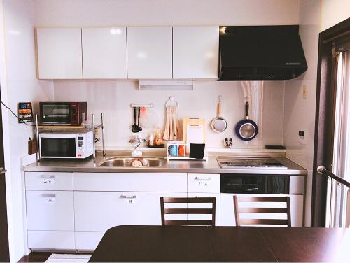 a kitchen with white cabinets and a sink and a microwave at Osaka Sinsei Guest House in Osaka