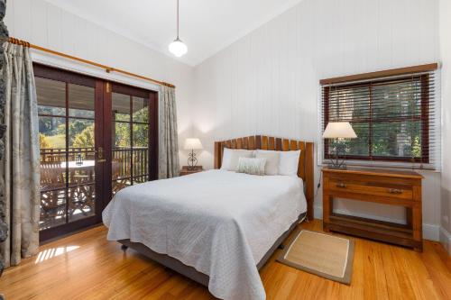 a bedroom with a bed and a desk and windows at Friday Creek Retreat in Coffs Harbour