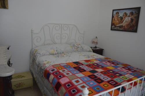 a bedroom with a bed with a colorful quilt at Appartamento in palazzina storica / Oberdan Suites in Alberobello