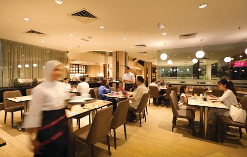 um grupo de pessoas sentadas em mesas em um restaurante em RHR Hotel Kajang em Kajang