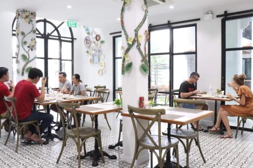 a group of people sitting at tables in a restaurant at Lanna Oriental Hotel in Chiang Mai