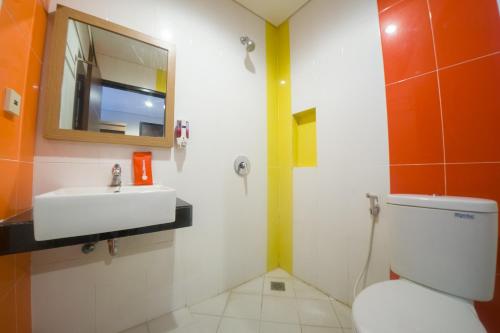uma casa de banho com um WC, um lavatório e um espelho. em Budget Hotel Ambon em Ambon