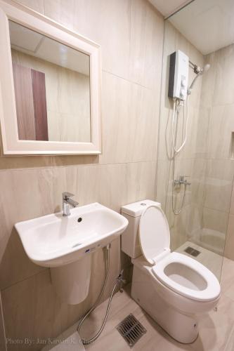 a bathroom with a toilet and a sink and a mirror at Griffin Hotel and Suites in Cebu City