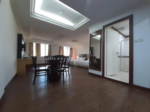 a dining room with a table and chairs and a bedroom at Sara Hotel in Labuan