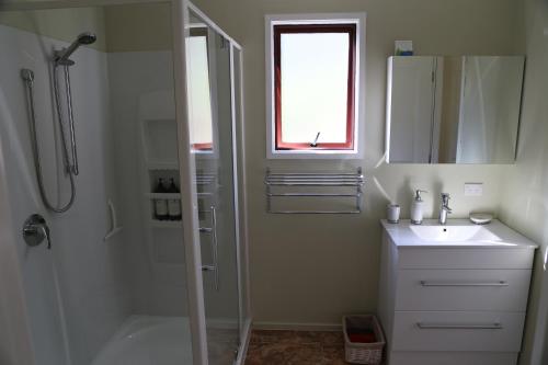 a white bathroom with a shower and a sink at The Sanctuary at The Havens Motueka River Valley in Tasman