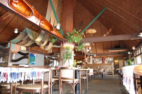 ein Restaurant mit Tischen, Stühlen und Surfbrettern an der Decke in der Unterkunft Amami Resort Bashayamamura in Amami