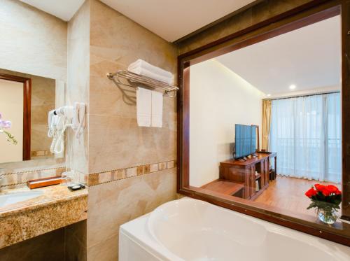 a bathroom with a tub and a sink and a mirror at Red Sun Nha Trang Hotel in Nha Trang