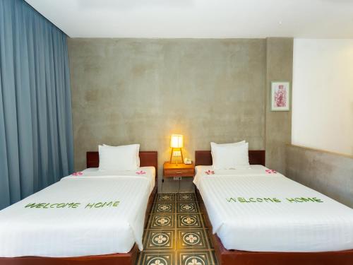 two beds in a small room with a lamp at Tanei Angkor Resort and Spa in Siem Reap