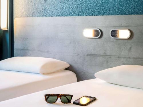 a pair of glasses sitting on top of two beds at ibis budget Bordeaux Centre - Gare Saint Jean in Bordeaux
