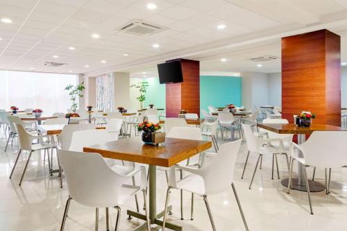 a dining room with tables and white chairs at Sleep Inn Mazatlan in Mazatlán
