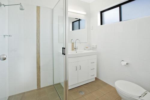 a bathroom with a toilet and a glass shower at Bega Village Motor Inn in Bega