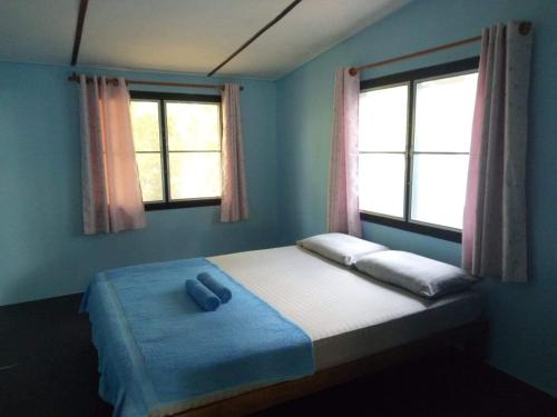 a bedroom with a bed with two pillows and two windows at TA YAI HOMESTAY (ตา ยาย โฮมสเตย์) in Ko Kood