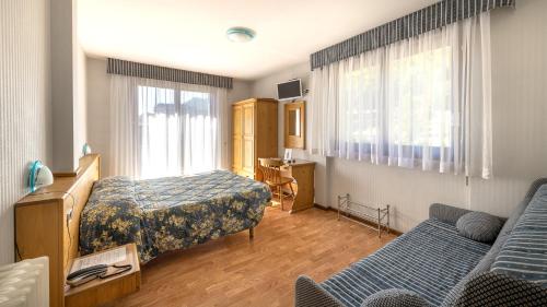 ein Hotelzimmer mit 2 Betten und einem Sofa in der Unterkunft Hotel Club Funivia in Aprica