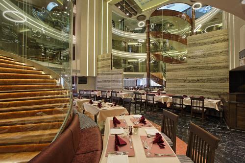 a restaurant with tables and chairs and a staircase at Bizz The Hotel in Rajkot