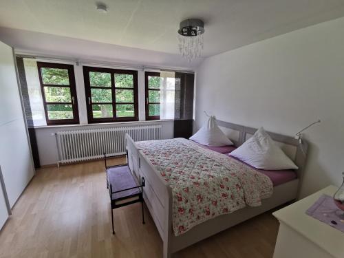 a bedroom with a bed and a chair and windows at Kucks-Ferienwohnung in Wiefelstede