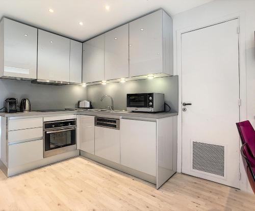 une cuisine avec des armoires blanches et un micro-ondes dans l'établissement 24 Août Sucquet, à Cannes