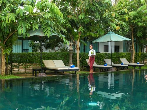 a man standing next to a swimming pool at Tanei Angkor Resort and Spa in Siem Reap
