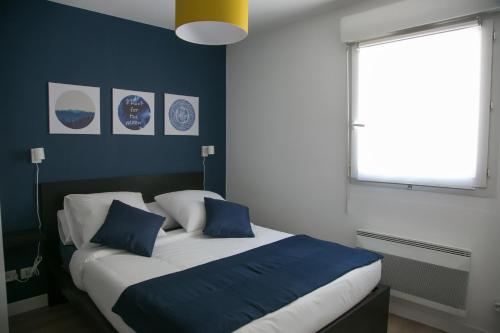 une chambre avec un lit avec des oreillers bleus et blancs dans l'établissement T2 proche Centre historique Gare St-Roch avec Parking, à Montpellier
