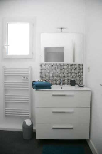 une salle de bain blanche avec un lavabo et un miroir dans l'établissement T2 proche Centre historique Gare St-Roch avec Parking, à Montpellier