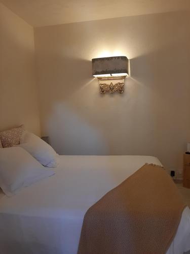 een slaapkamer met 2 bedden en een lampje aan de muur bij Petit Appart Douillet au Cœur de la Haute-ville in Bonifacio