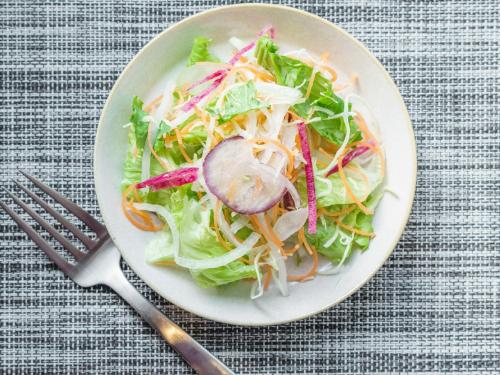 帯広市にあるスーパーホテル Premier 帯広駅前のテーブルの上にフォークが置かれたサラダの皿