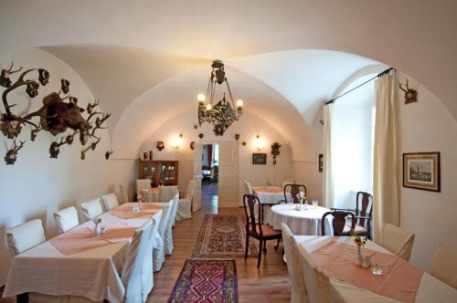 a dining room with white tables and chairs and a chandelier at Schlosshotel Zamek Zdikov in Zdíkov