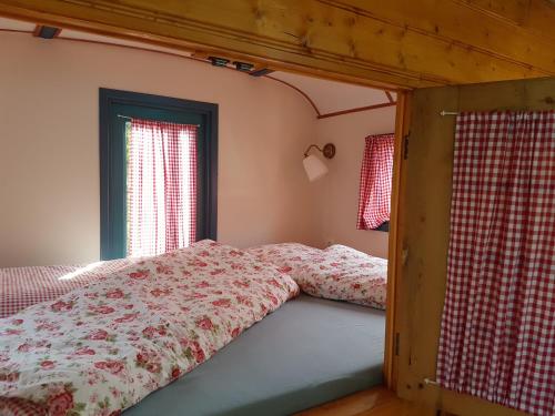 1 cama en un dormitorio con 2 ventanas y colcha en Gezellig pipowagen in Oostvoorne, en Oostvoorne