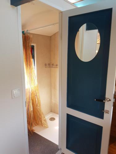Baño con puerta azul y espejo en Gezellig pipowagen in Oostvoorne, en Oostvoorne