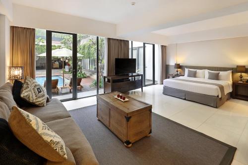 a bedroom with a bed and a living room at Hotel NEO+ Kuta Legian by ASTON in Legian