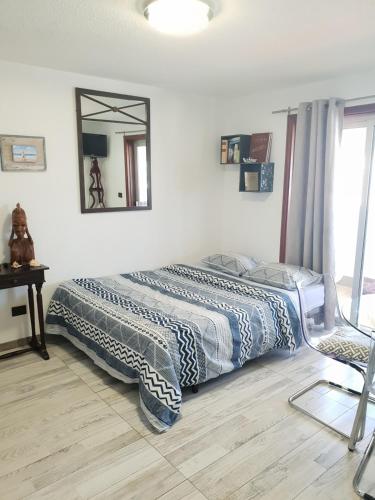 1 dormitorio con cama y espejo en la pared en Lovely studia in Las Galletas con nice sea view, en Las Galletas