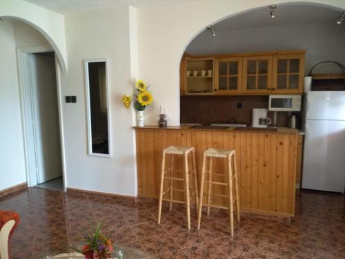 a kitchen with a white refrigerator and two stools at Szemes Apartman Balaton in Balatonszemes