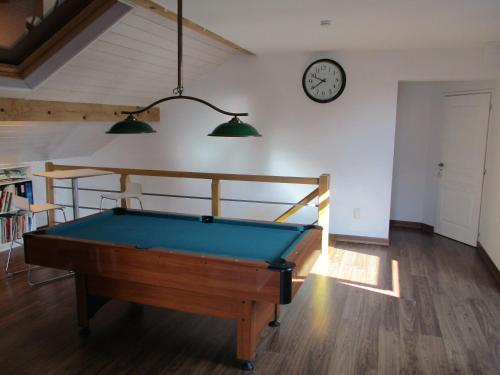einen Billardtisch in einem Zimmer mit einer Uhr an der Wand in der Unterkunft Chez Fabienne in Peyrieu